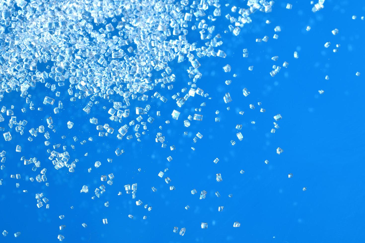 Top view of white crystal sugar isolated on blue background photo