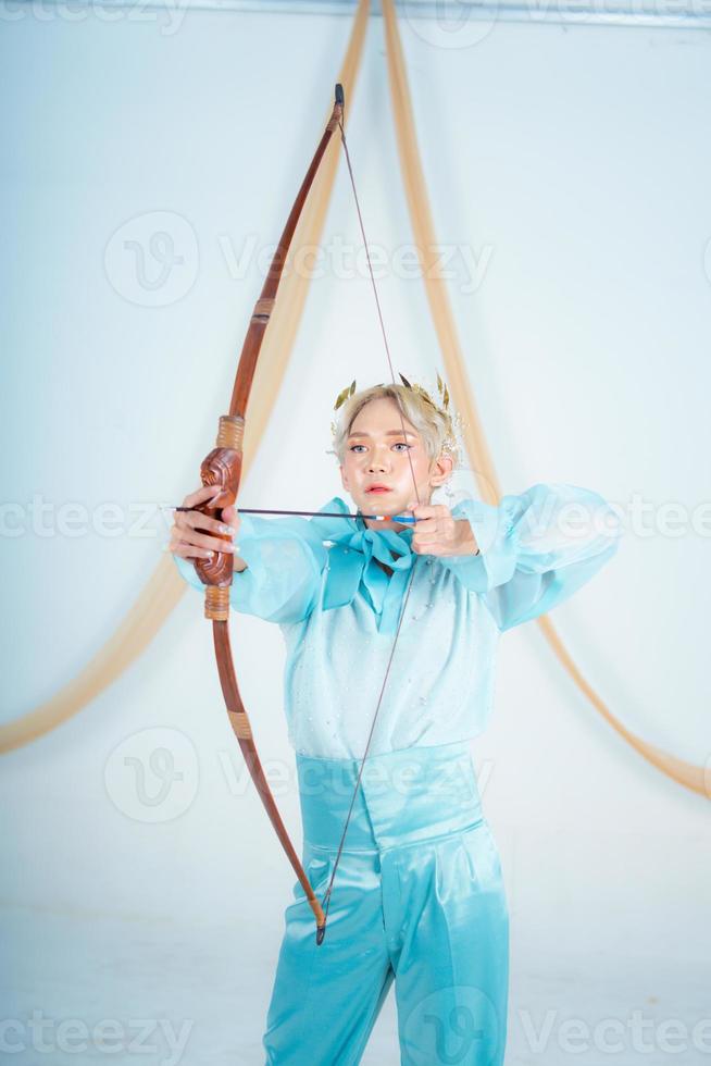 an Asian woman with blonde hair holding an arrow while wearing a blue dress photo