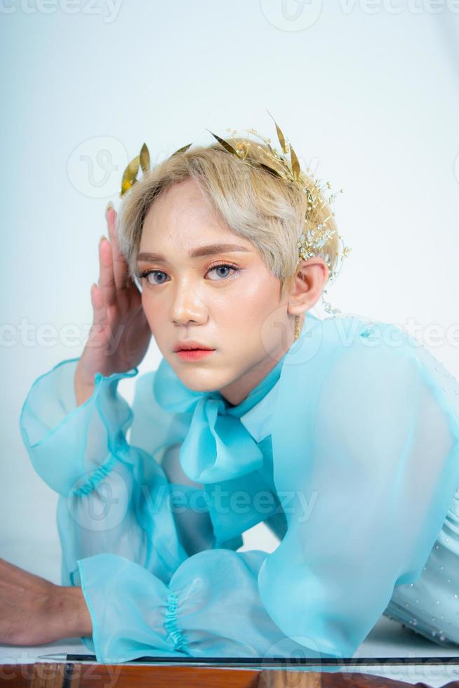 a woman with blonde hair and a blue dress posing with curled arms and a blushing face photo