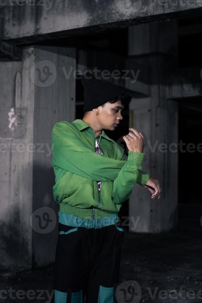 an Asian man smiles while wearing a green parachute jacket and black pants photo
