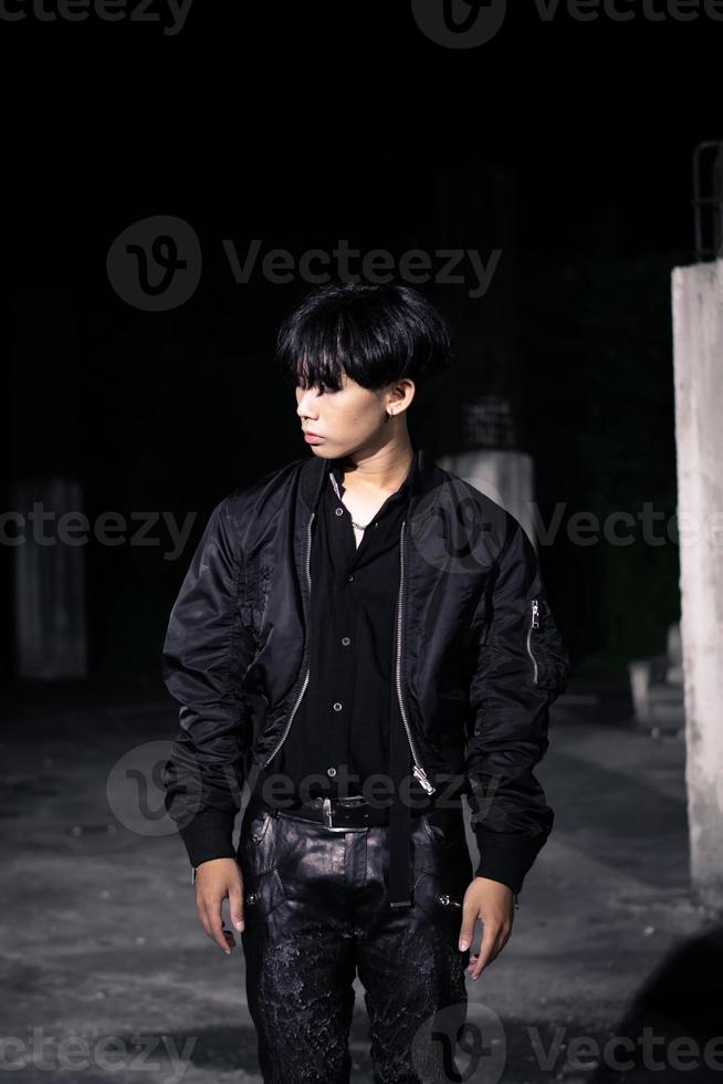 an asian man in a black parachute jacket posing very manly in a building photo