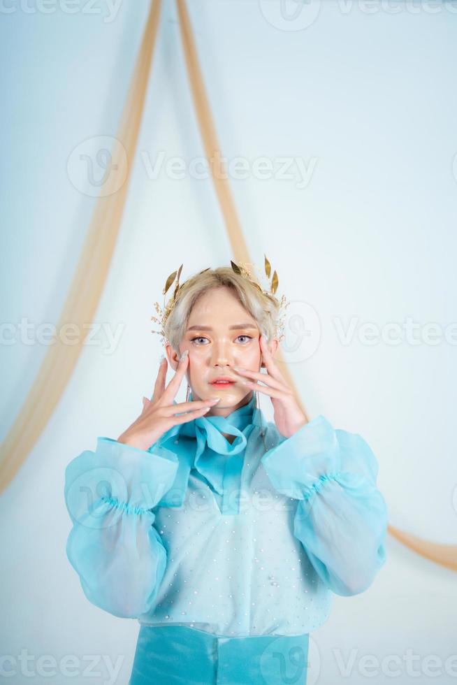 an elegant woman with blonde hair wearing a golden crown and a blue dress photo