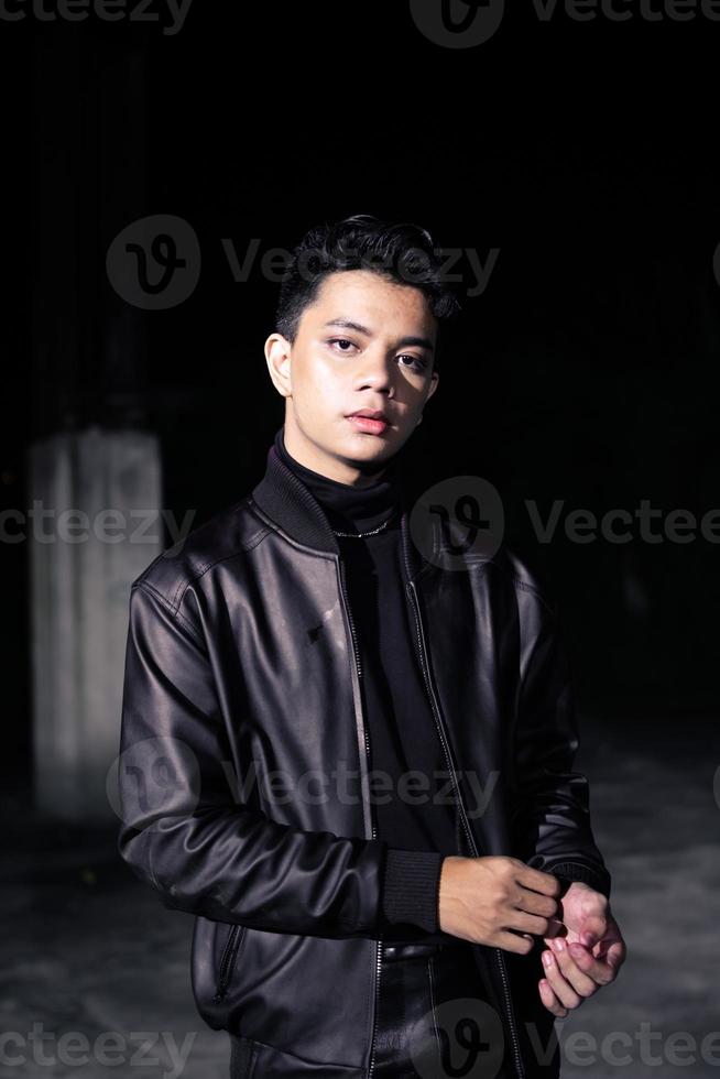 an Asian man wearing a leather jacket and black pants with a handsome face photo