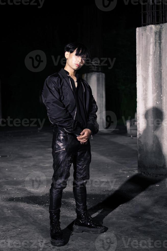 an asian man in a black parachute jacket posing very manly in a building photo