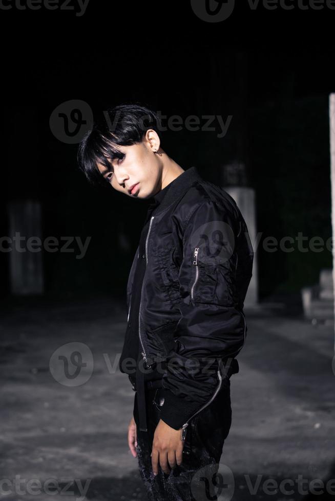 an asian man in a black parachute jacket posing very manly in a building photo