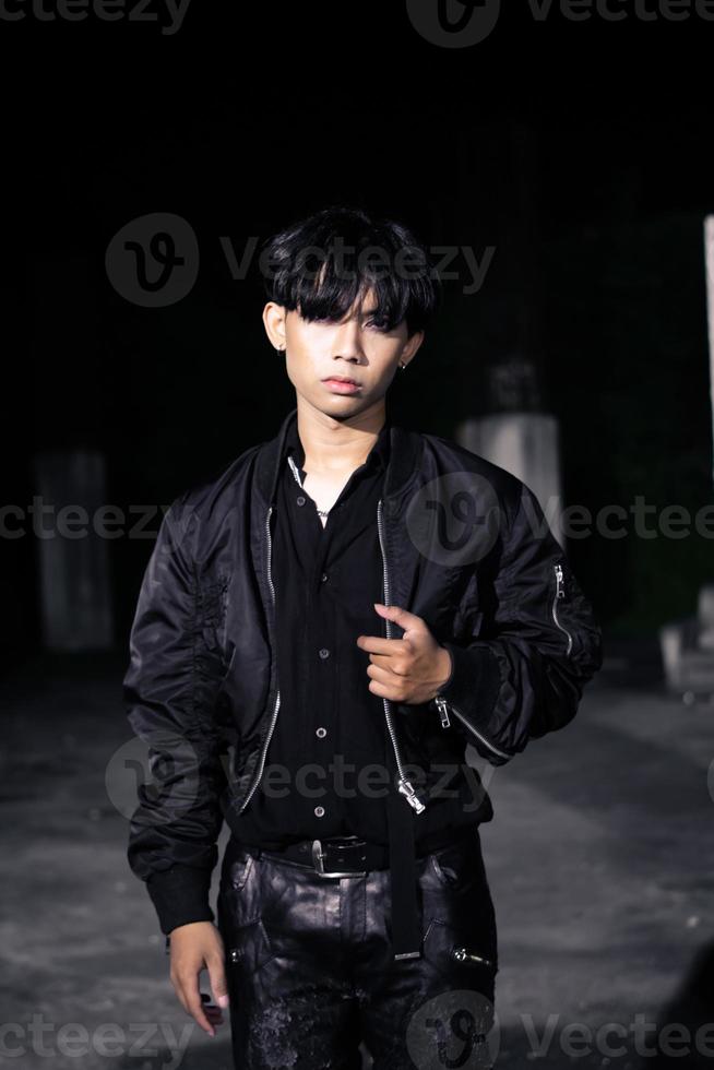 an asian man in a black parachute jacket posing very manly in a building photo