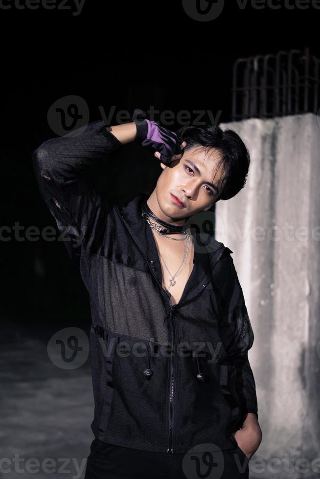 an Asian man dressed all in black and black hair posing as masculine photo