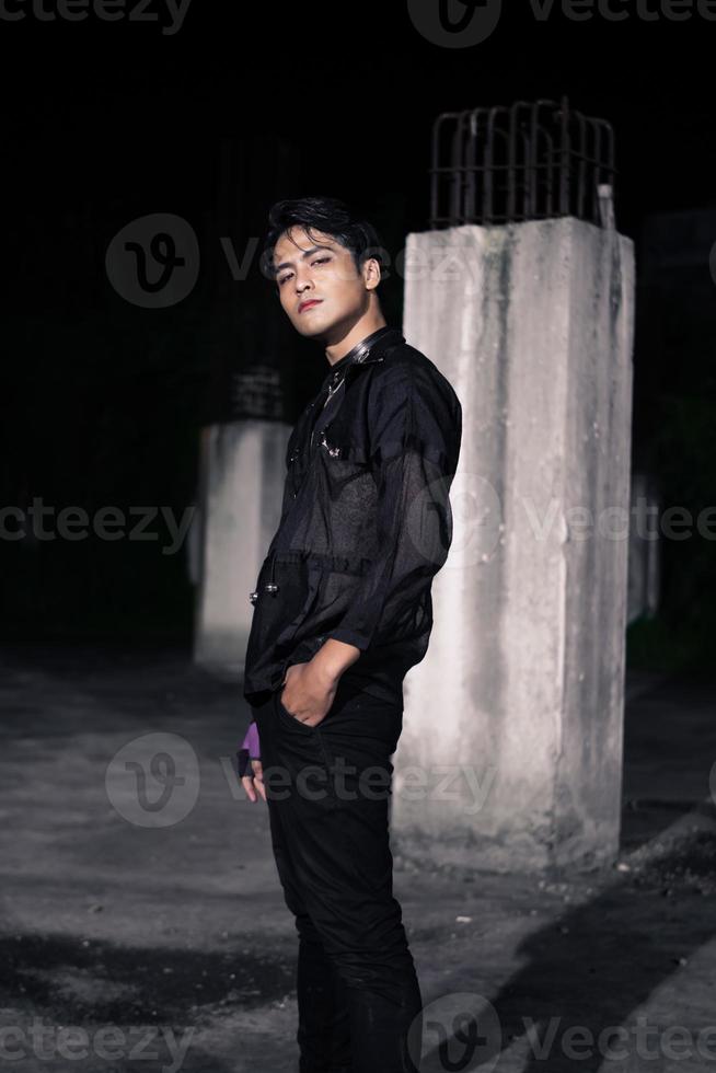 an Asian man dressed all in black and black hair posing as masculine photo