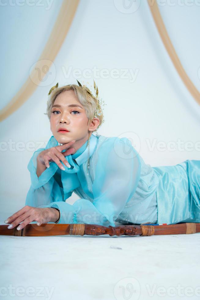 a princess in a blue dress posing on the floor with a bow photo