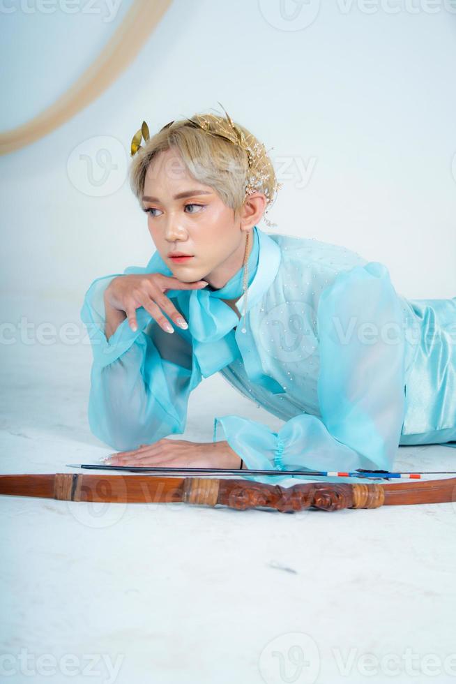 a princess in a blue dress posing on the floor with a bow photo