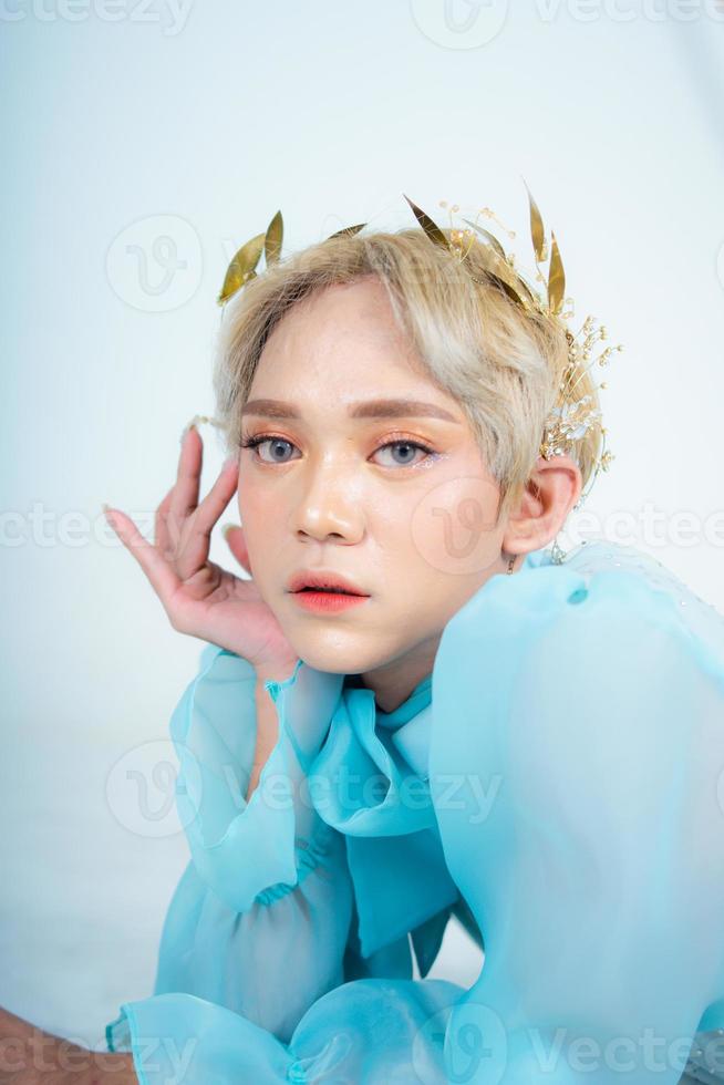 a woman with blonde hair and a blue dress posing with curled arms and a blushing face photo