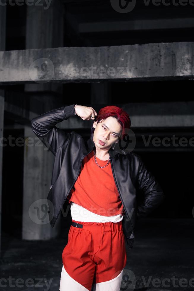 an asian man in a red shirt and black jacket posing with his hands photo