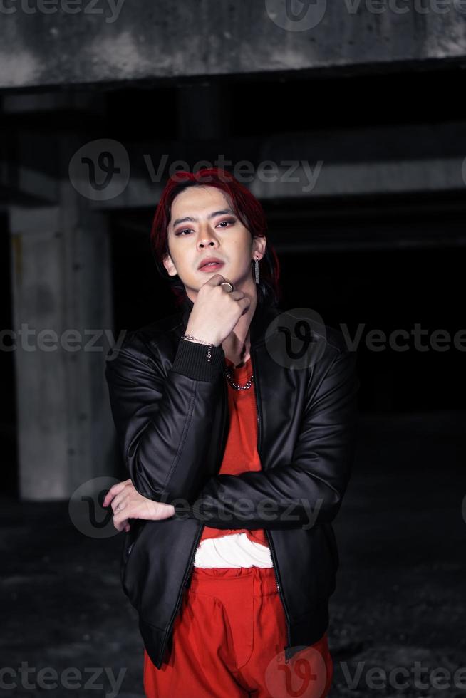 an asian man in a red shirt and black jacket posing with his hands photo