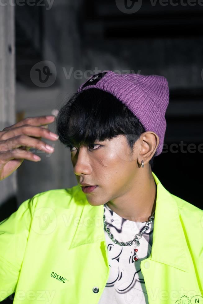 an asian man in a lime colored jacket leaning against a disused building pillar looking very handsome photo