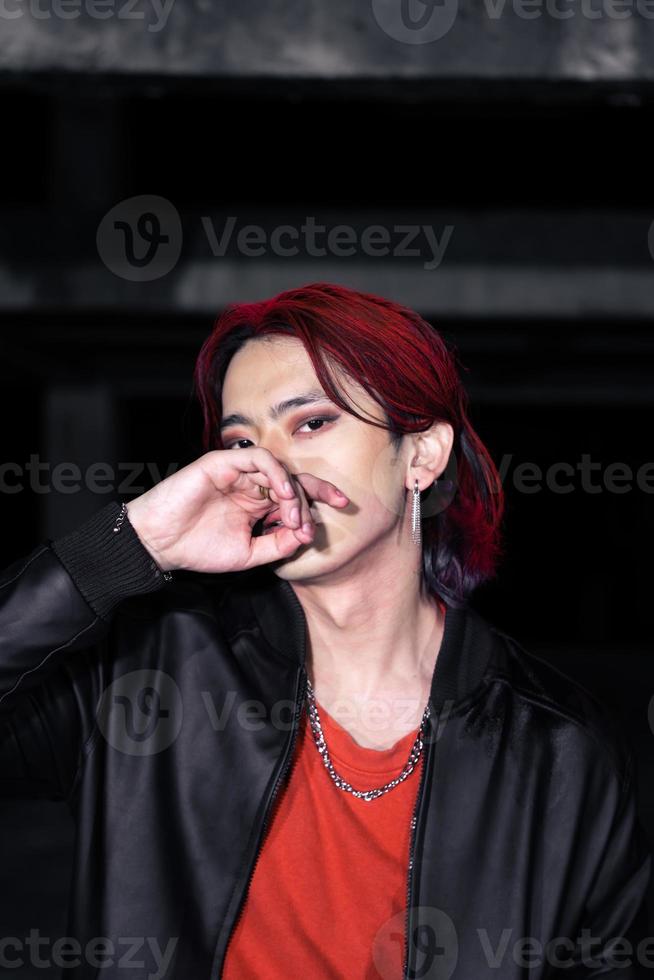 an asian man in a red shirt and earrings in his ears is standing photo