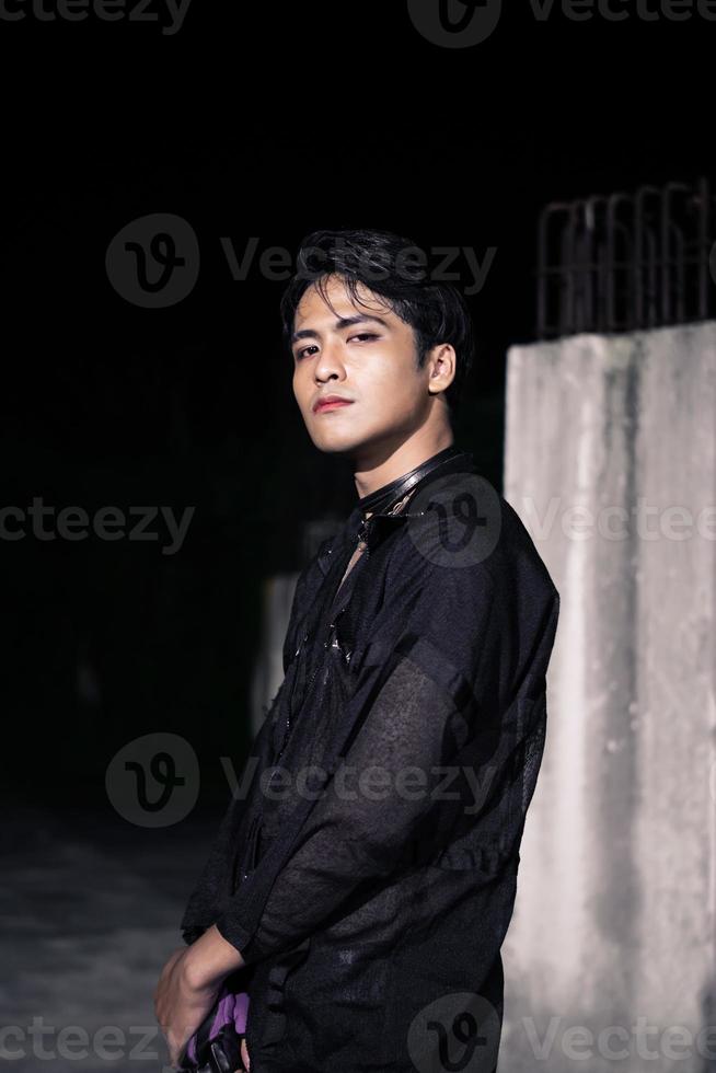 an Asian man dressed all in black and black hair posing as masculine photo