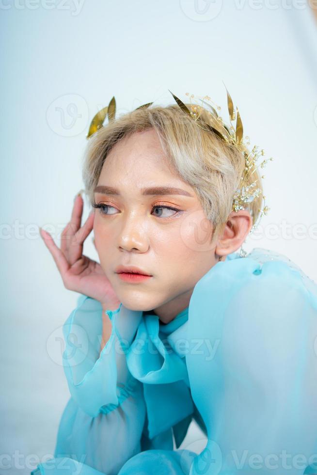 a woman with blonde hair and a blue dress posing with curled arms and a blushing face photo