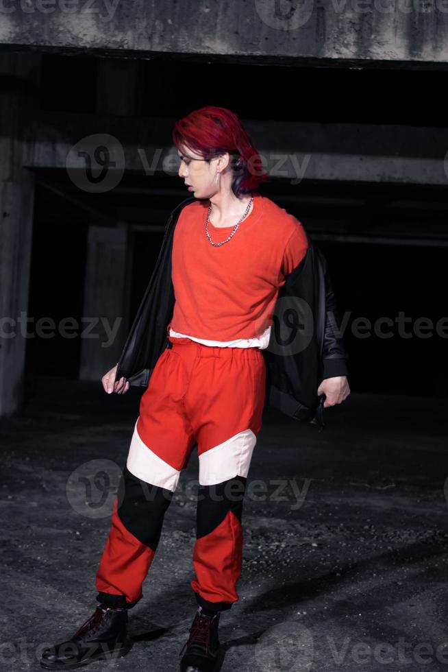 an asian man with red hair and a black jacket is posing in an abandoned building photo