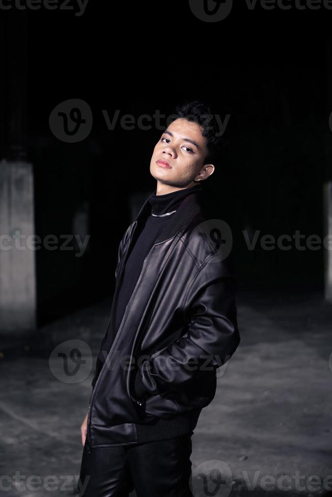 an Asian man wearing a leather jacket and black pants with a handsome face photo