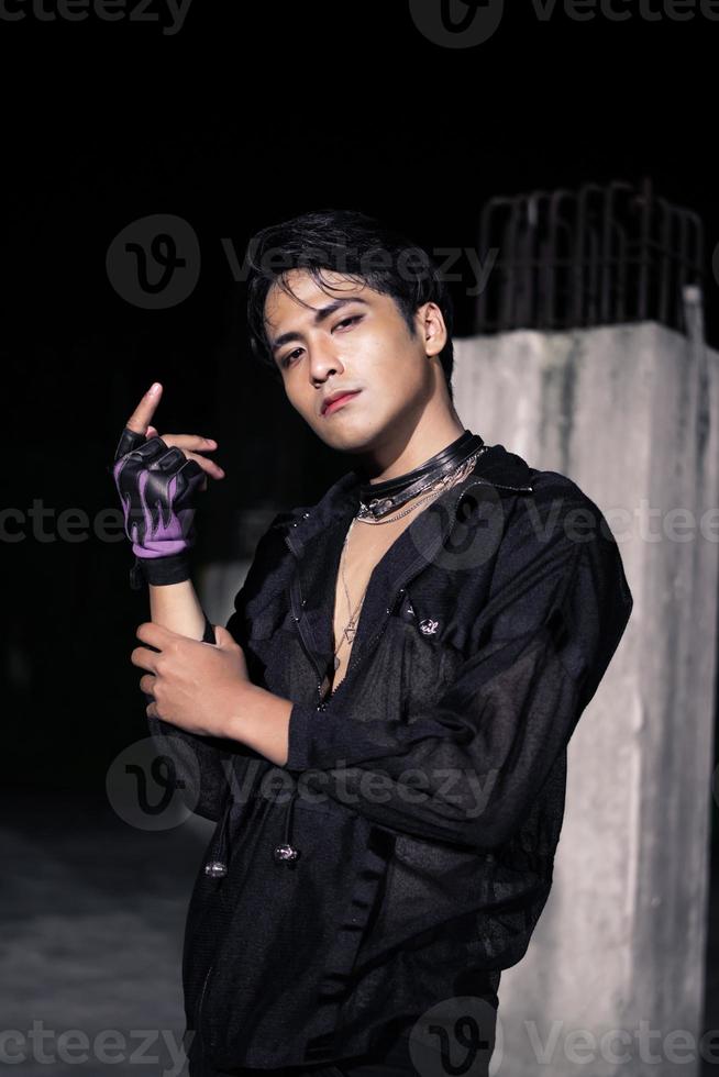 an Asian man dressed all in black and black hair posing as masculine photo