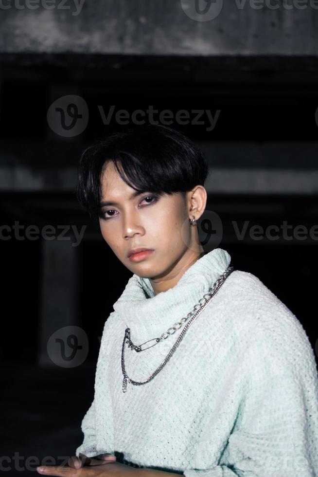 an asian man posing in a white sweater and a chain necklace around his neck photo