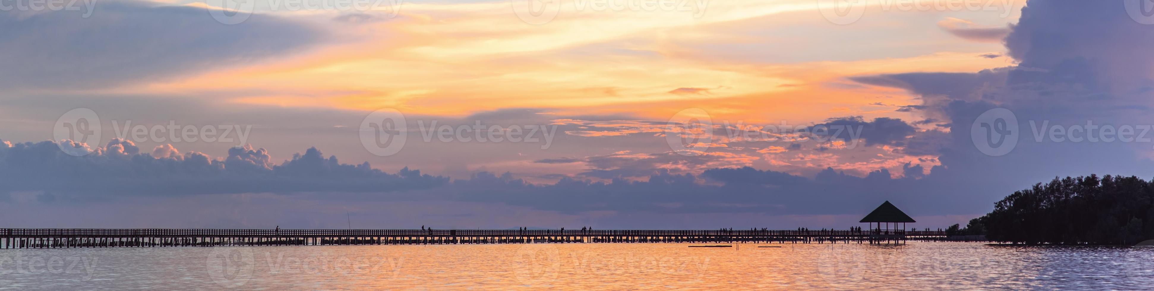 boardwalk on the sea in distance with sunset photo