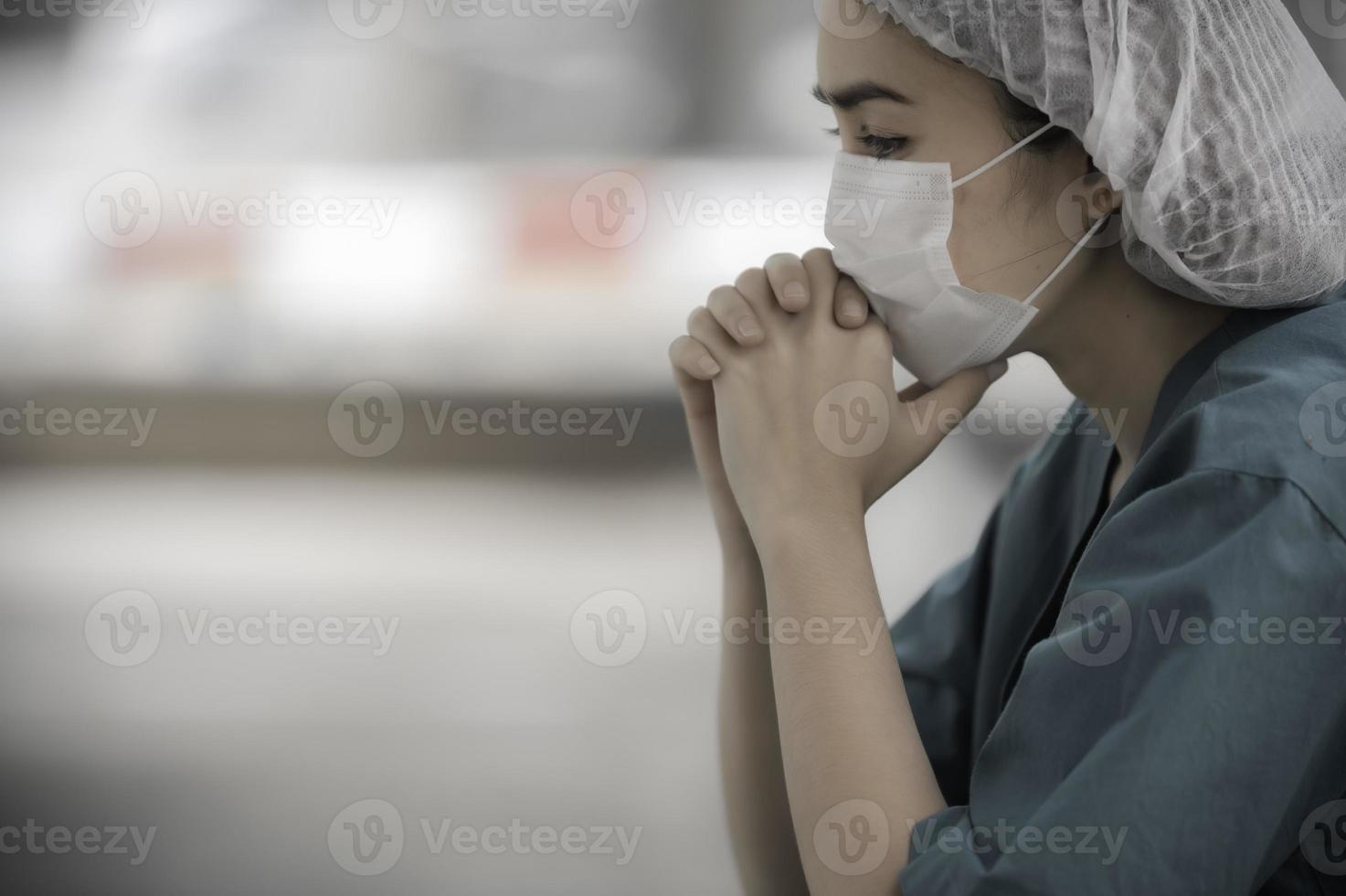 Tired depressed female asian scrub nurse wears face mask blue uniform sits on hospital floor,Young woman doctor stressed from hard work photo