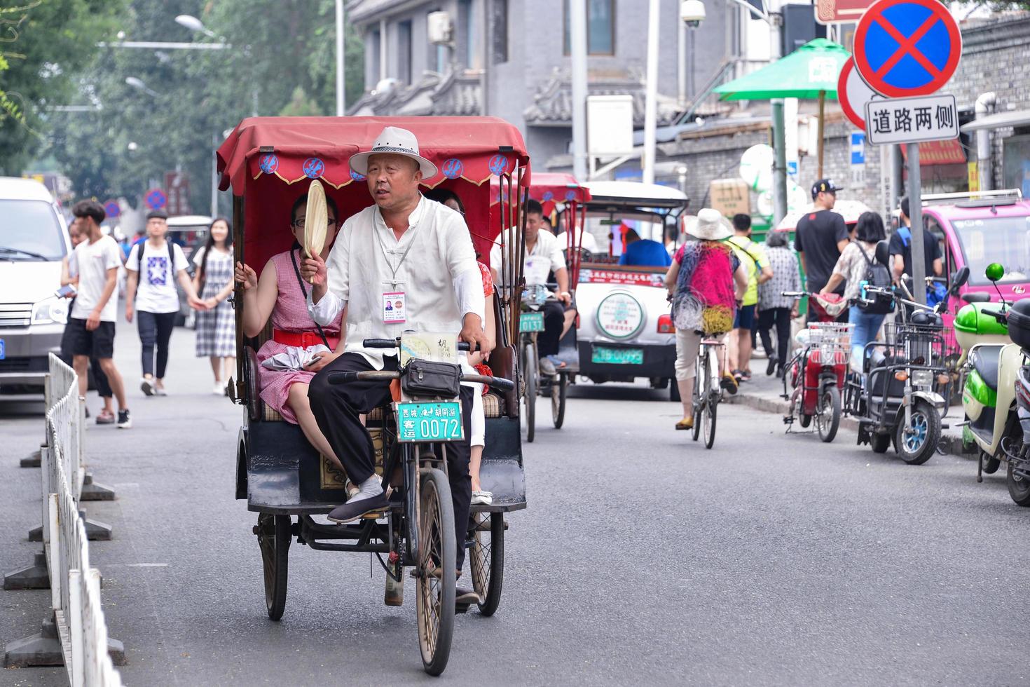 BEIJING, CHINA - JUL 03, 2016-Tourists in a rickshaw in a hutong, Ancient hutongs are formed by alleys that represent an important cultural element of the city of Beijing photo