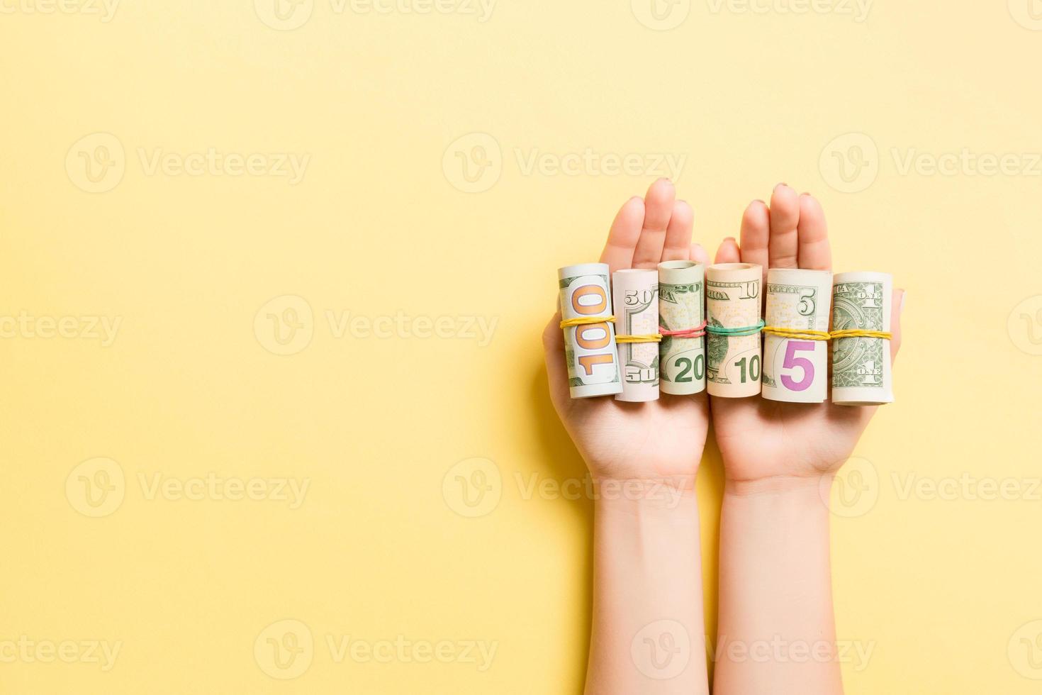 Top view of female hands holding a lot of rolled up dollar banknotes on colorful background. Poverty concept. Credit concept with copy space photo