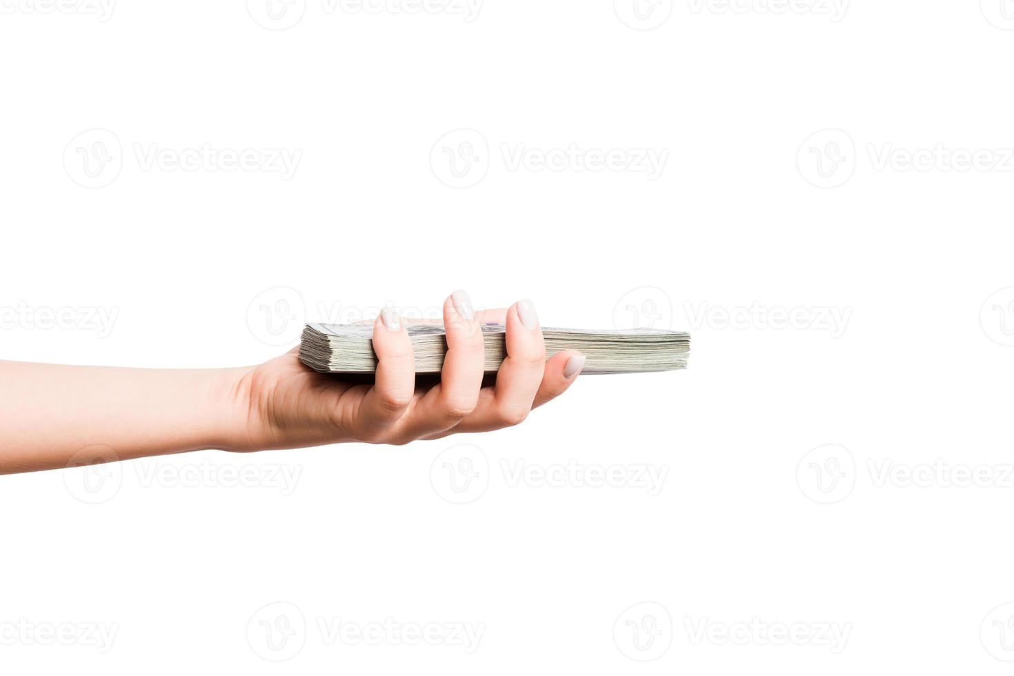 Female hand giving a bundle of dollar bills on white isolated background. Power and wealth concept photo