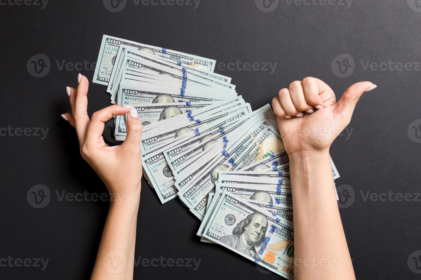 parte superior ver de uno cien dólar cuentas en uno mano y demostración bueno y pulgar arriba gesto con otro mano en vistoso antecedentes. prosperidad y fortuna concepto foto