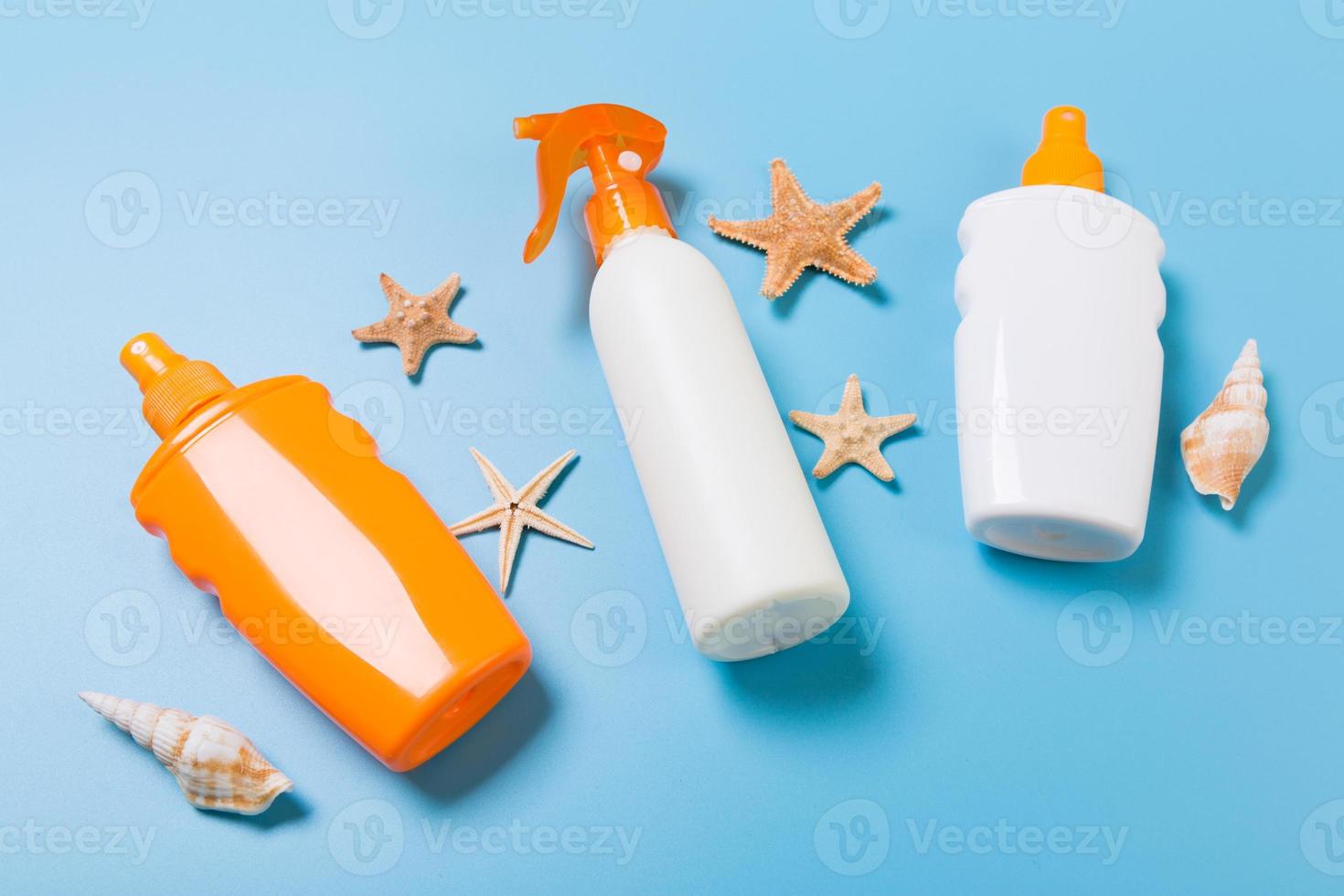 Sunscreen bottles with seashells on blue table top view photo