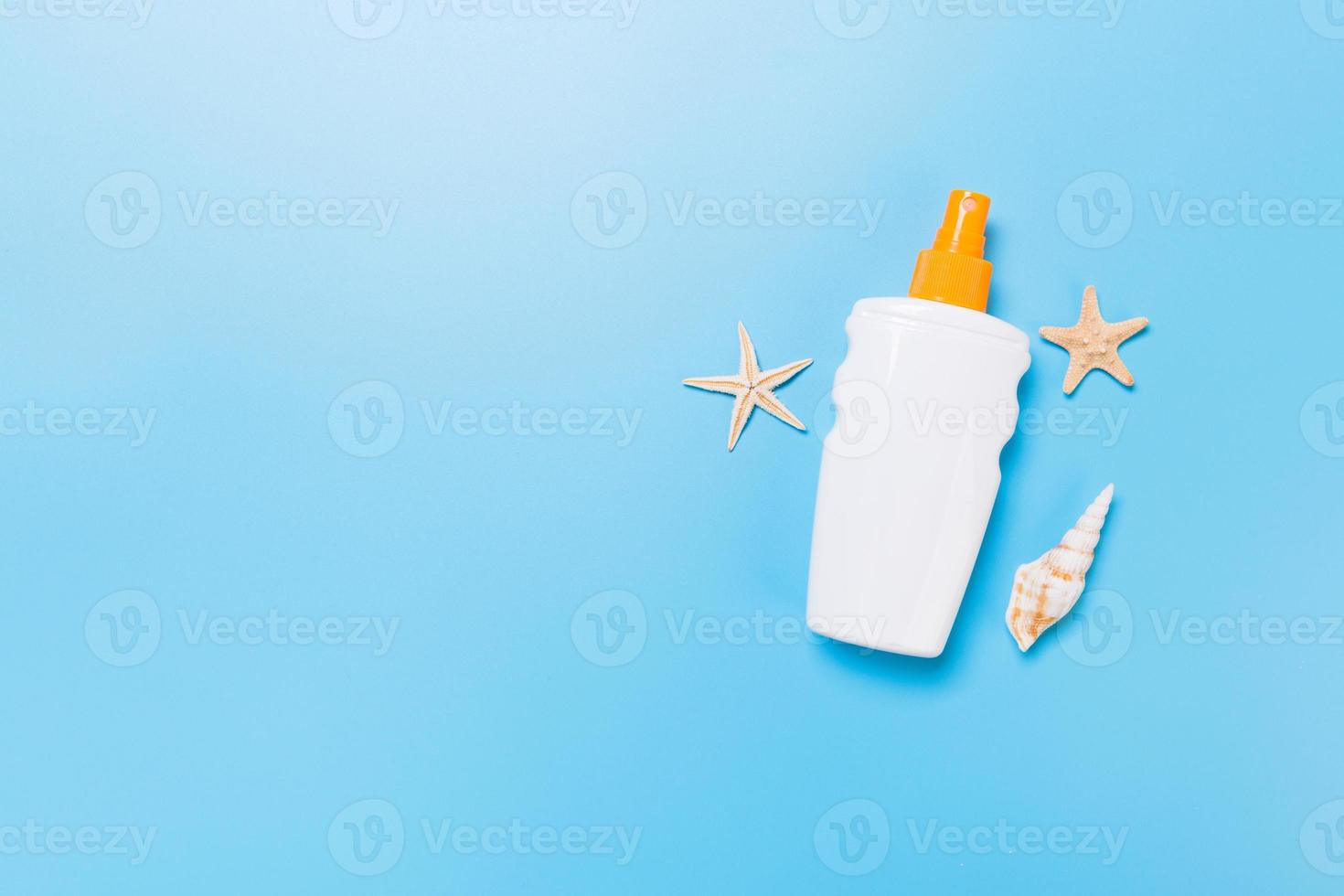 sunscreen cream with starfish and seashells in bottles on blue background, top view photo