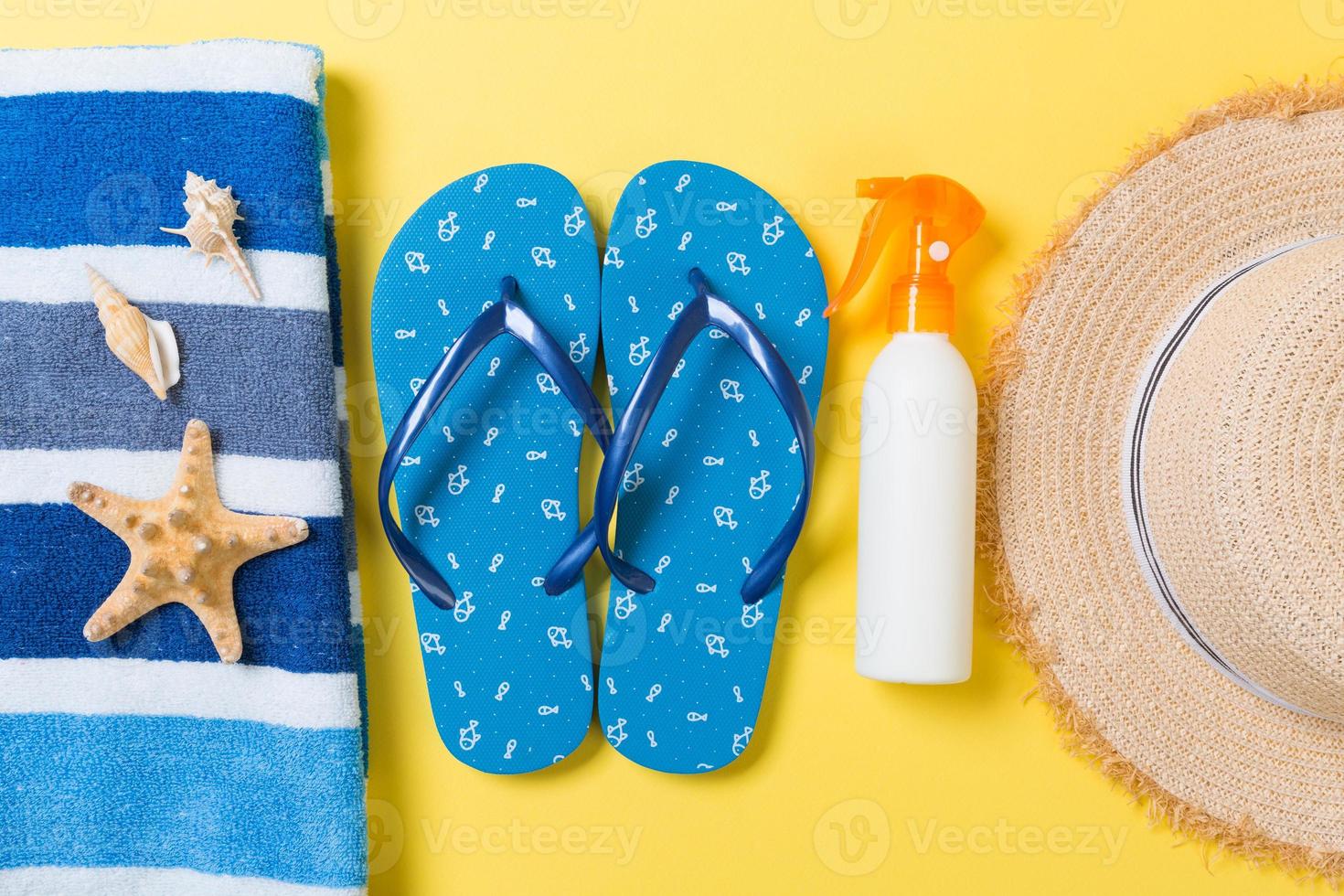 flip flops, straw hat, starfish, sunscreen bottle, body lotion spray on yellow background top view . flat lay summer beach sea accessories background, travel concept photo