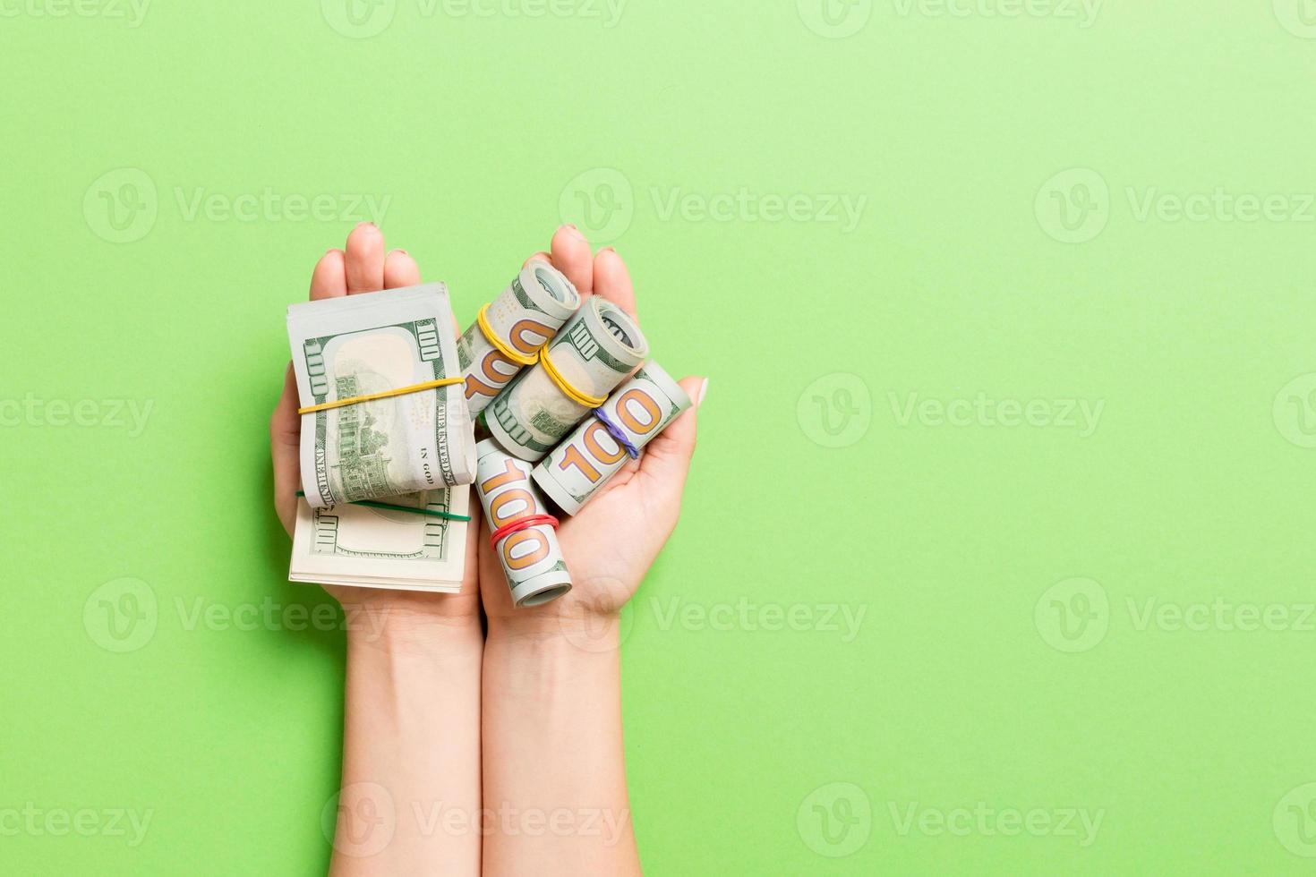 Top view of rolled up in tubes dollar bills in female palms on colorful background. Poverty and debt concept with empty space for your design photo
