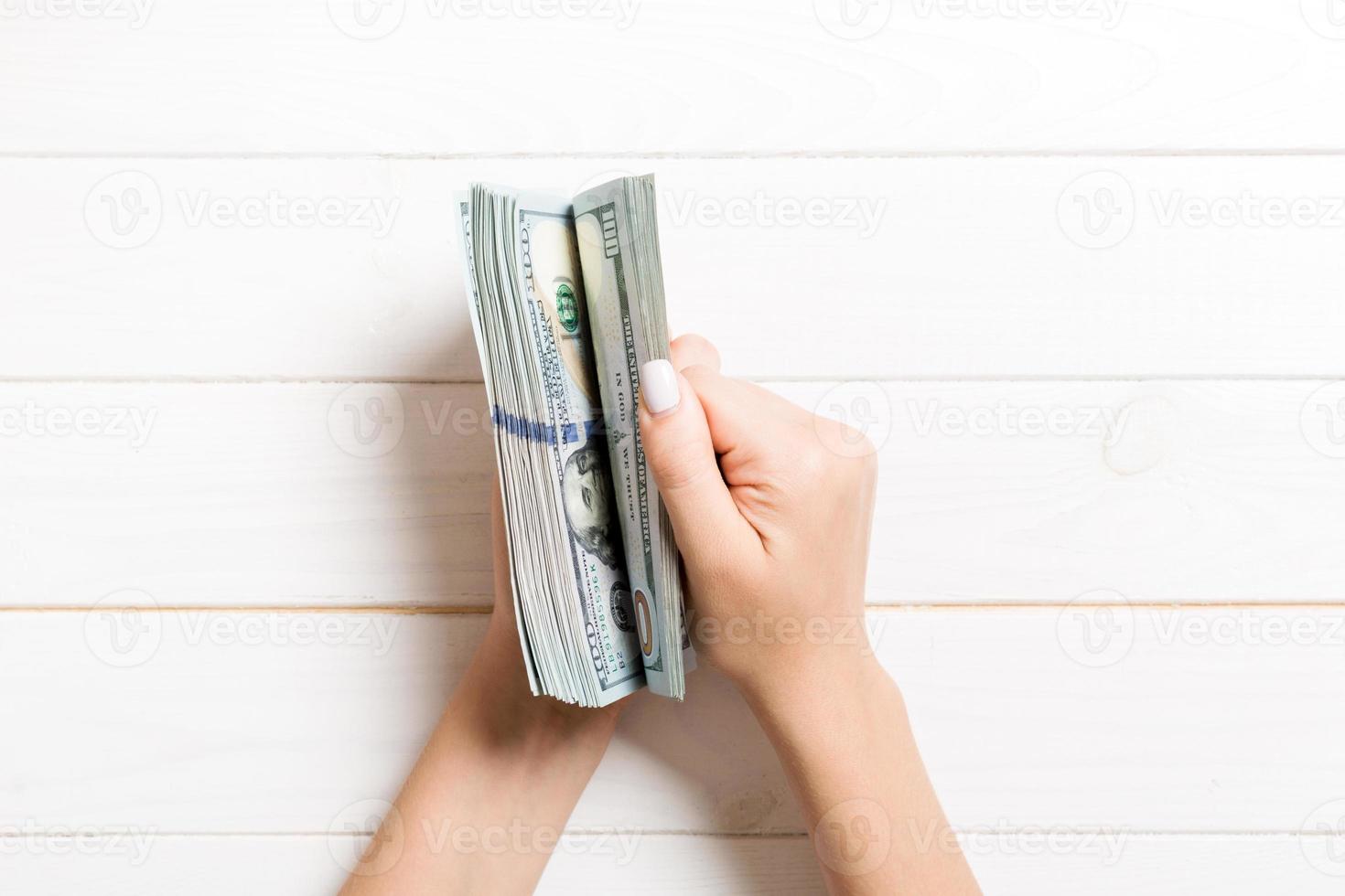 Top view of female hands counting money. One hundred dollar banknotes on wooden background. Salary concept. Bribe concept photo