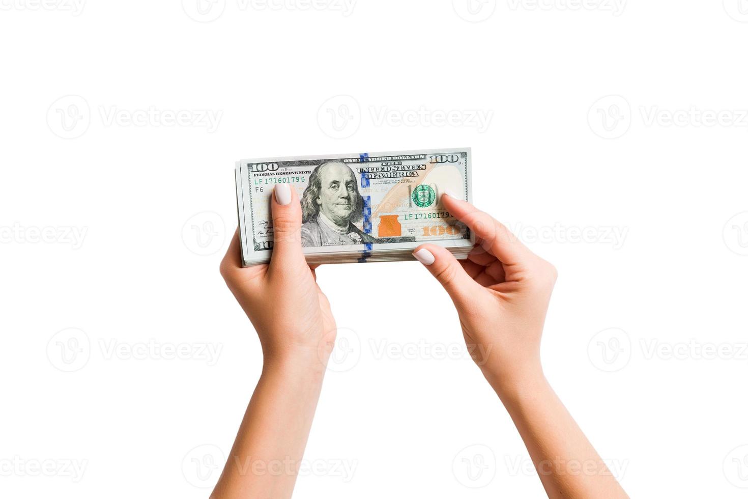 Female hand giving a bundle of dollar bills on white isolated background. Top view of power and wealth concept photo