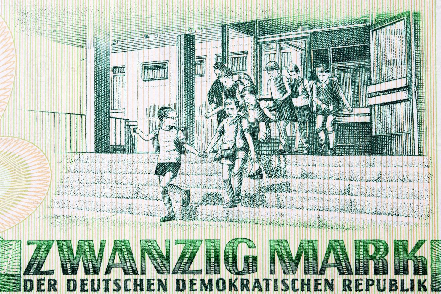 Several young children exiting a school from East German money photo