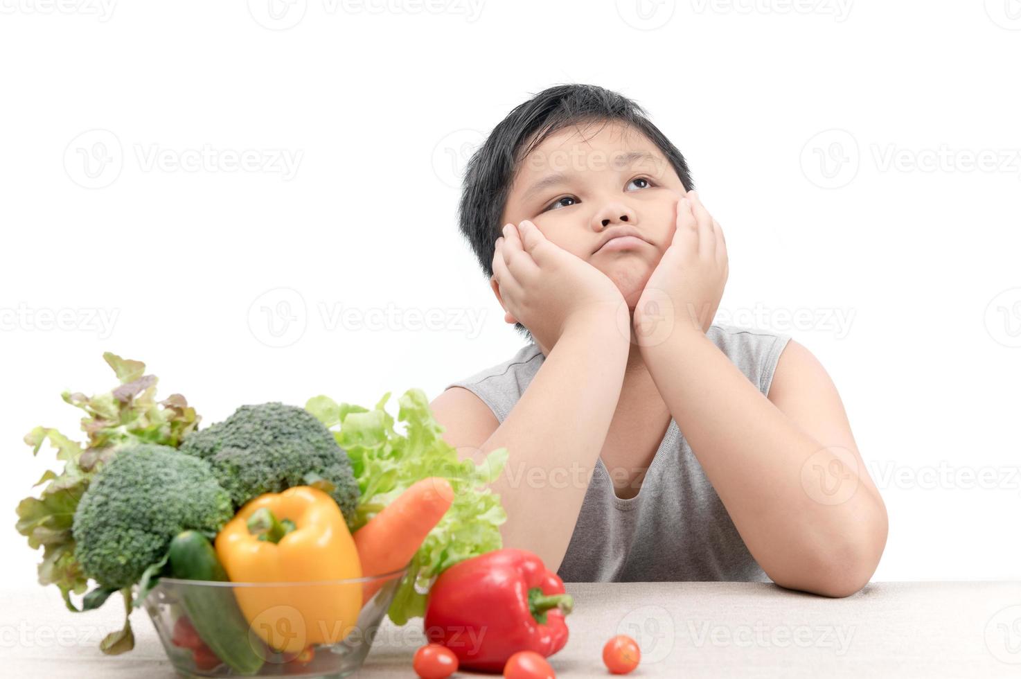 boy with expression of disgust against vegetables photo