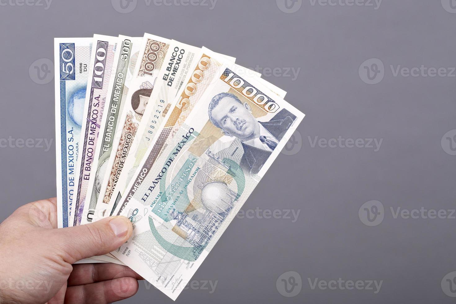 Old Mexican money in the hand on a gray background photo