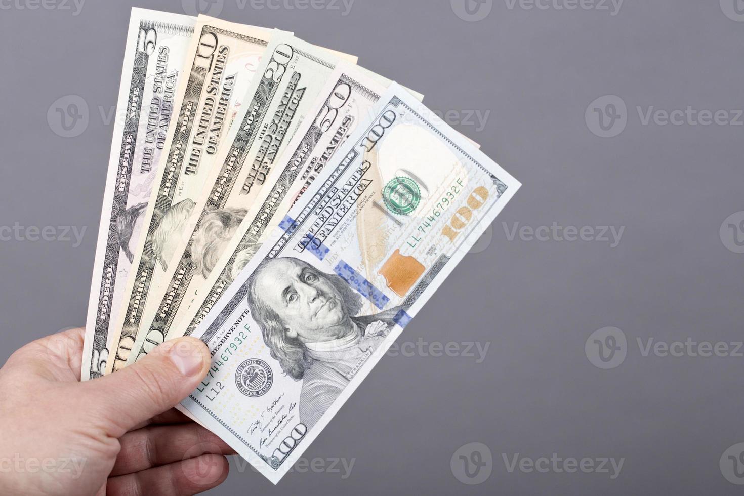 dinero desde Estados Unidos en el mano en un gris antecedentes foto