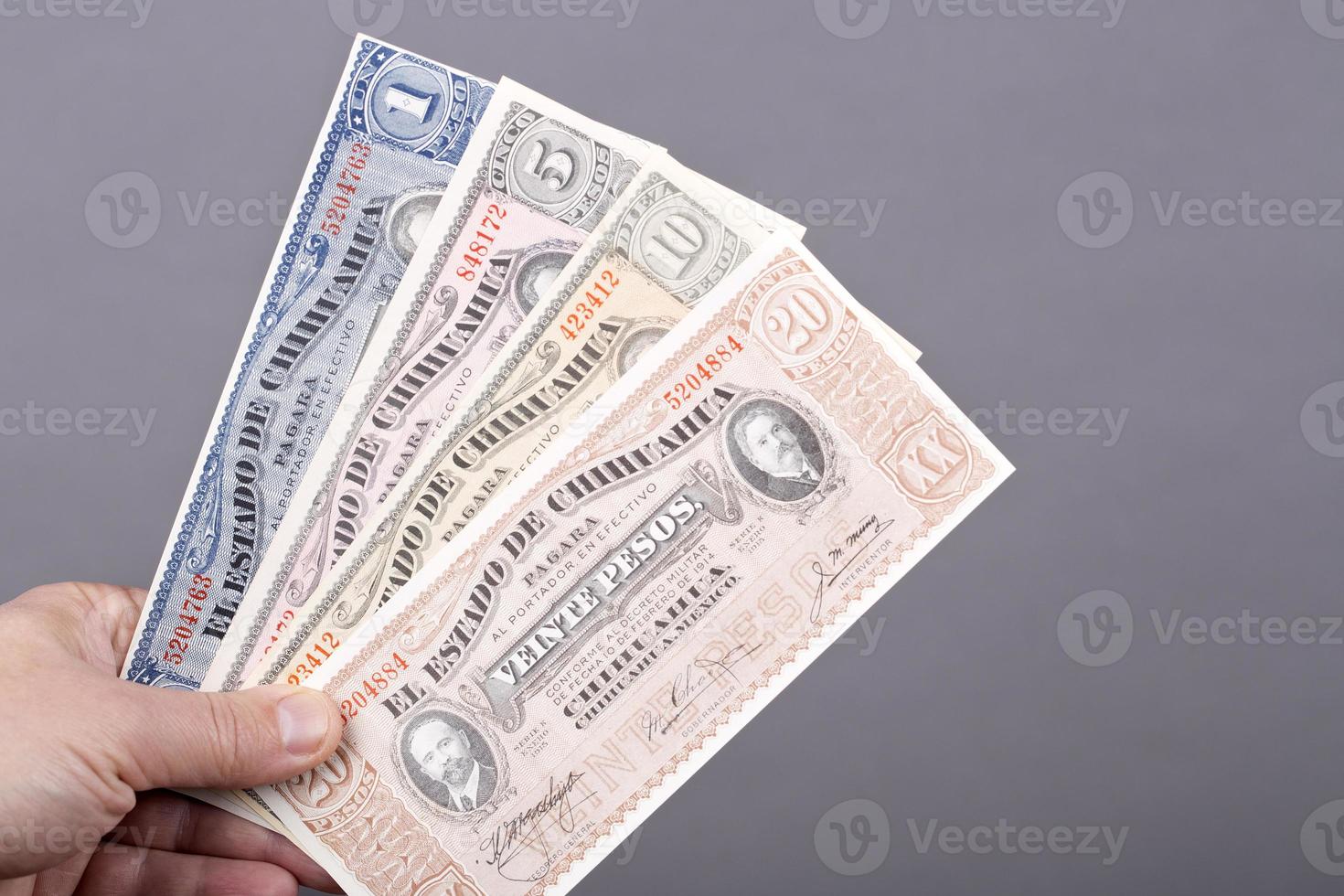 Old Mexican money in the hand on a gray background photo