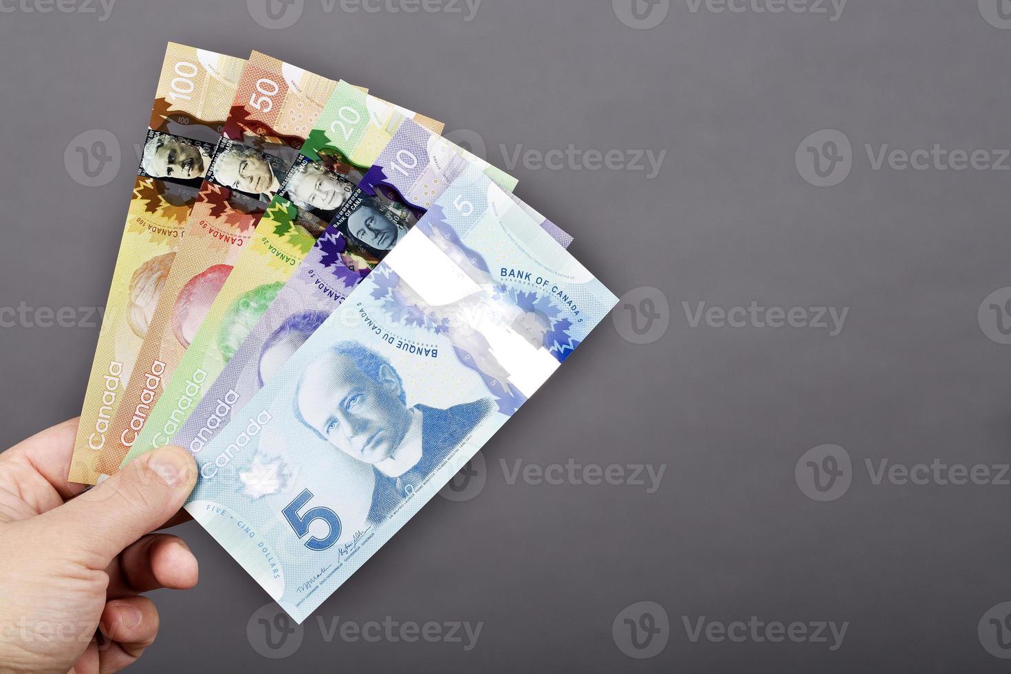 Money from Canada in the hand on a gray background photo