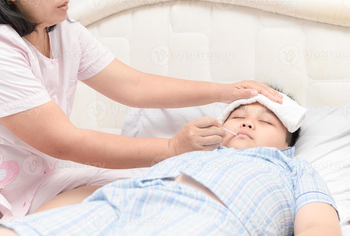 enfermo niño con alto fiebre tendido en cama foto