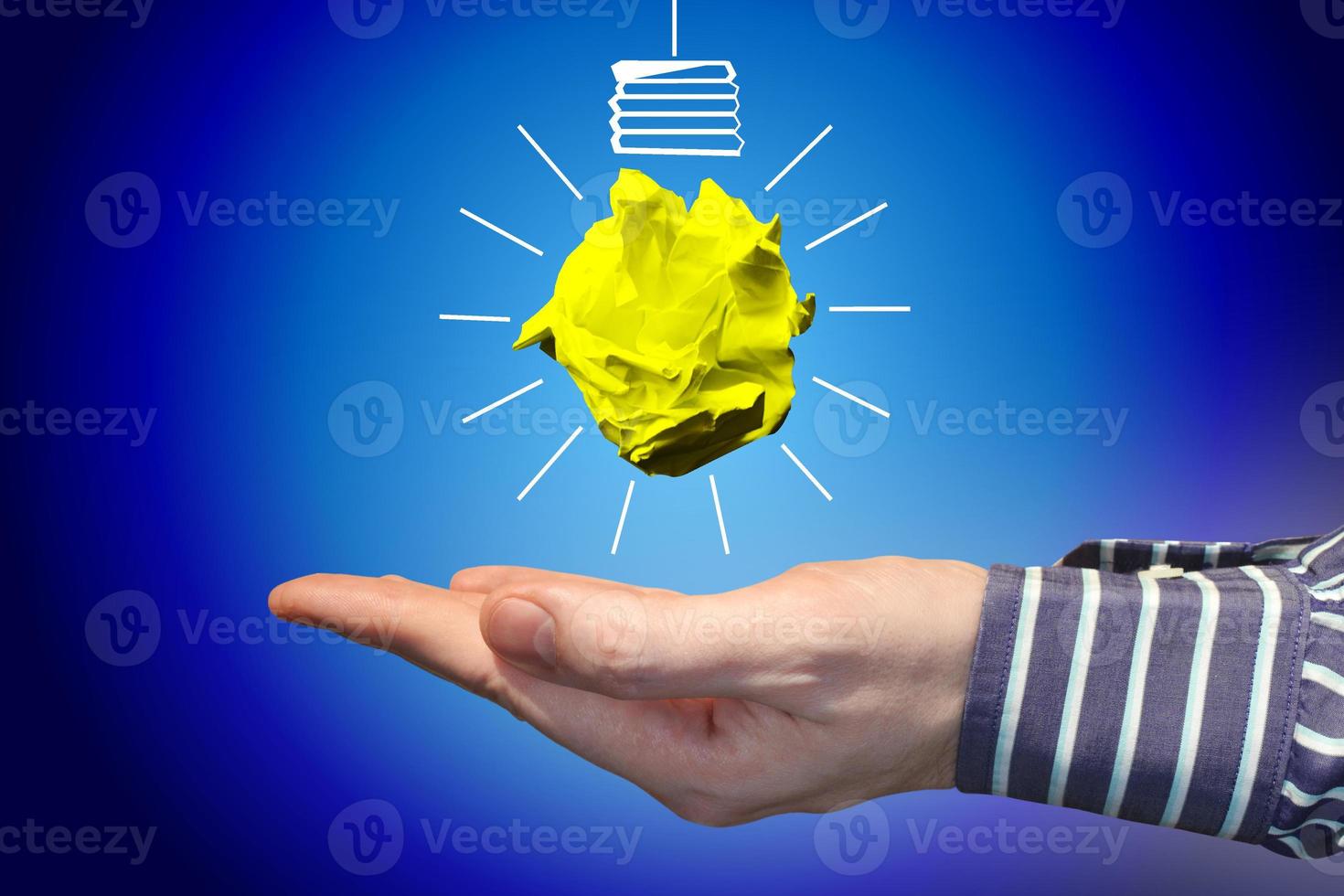 Light Bulb Icon Made with Crumpled Paper and Human Hand - Idea, Creativity Concept photo