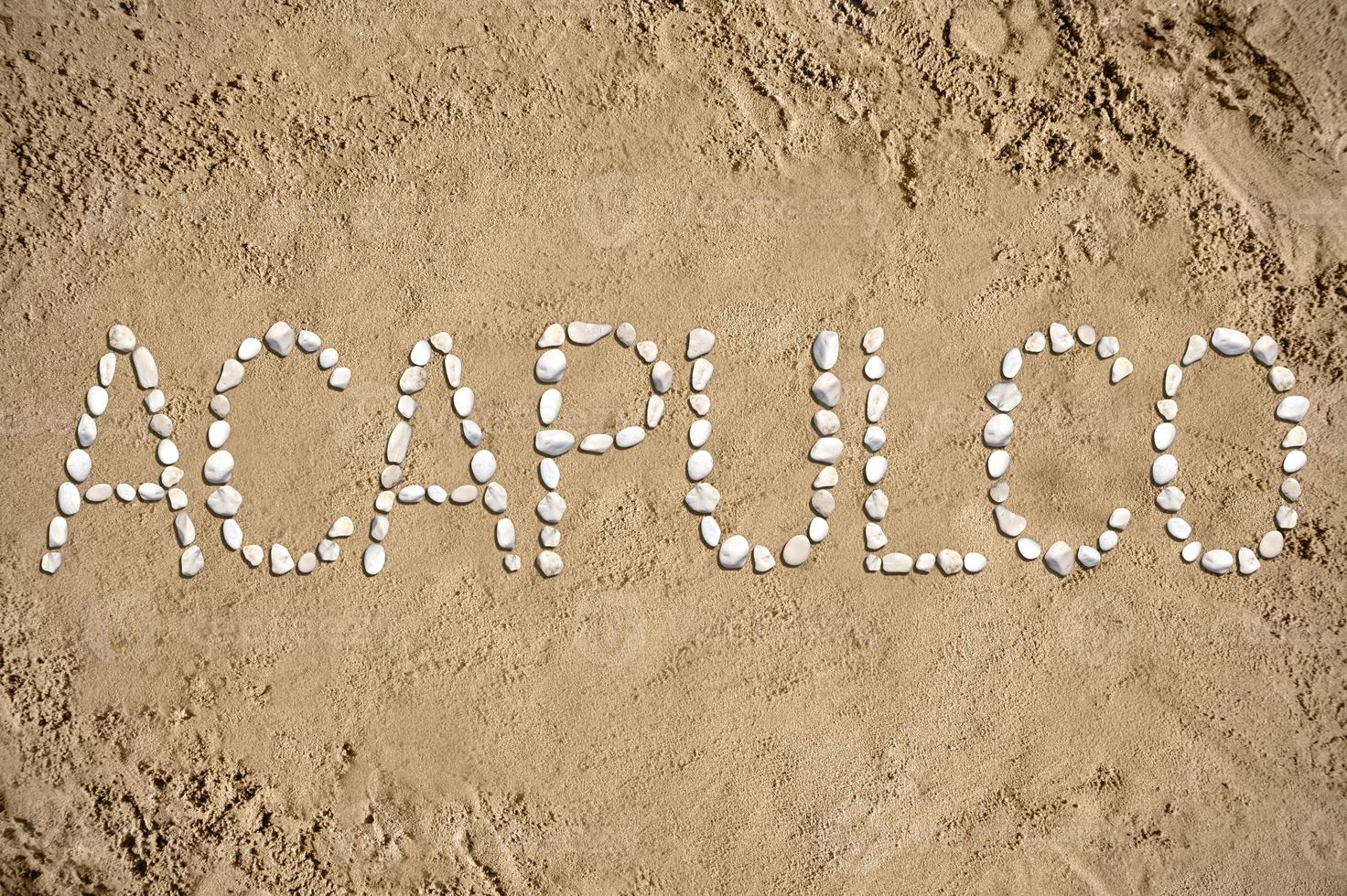 acapulco - palabra hecho con piedras en arena foto