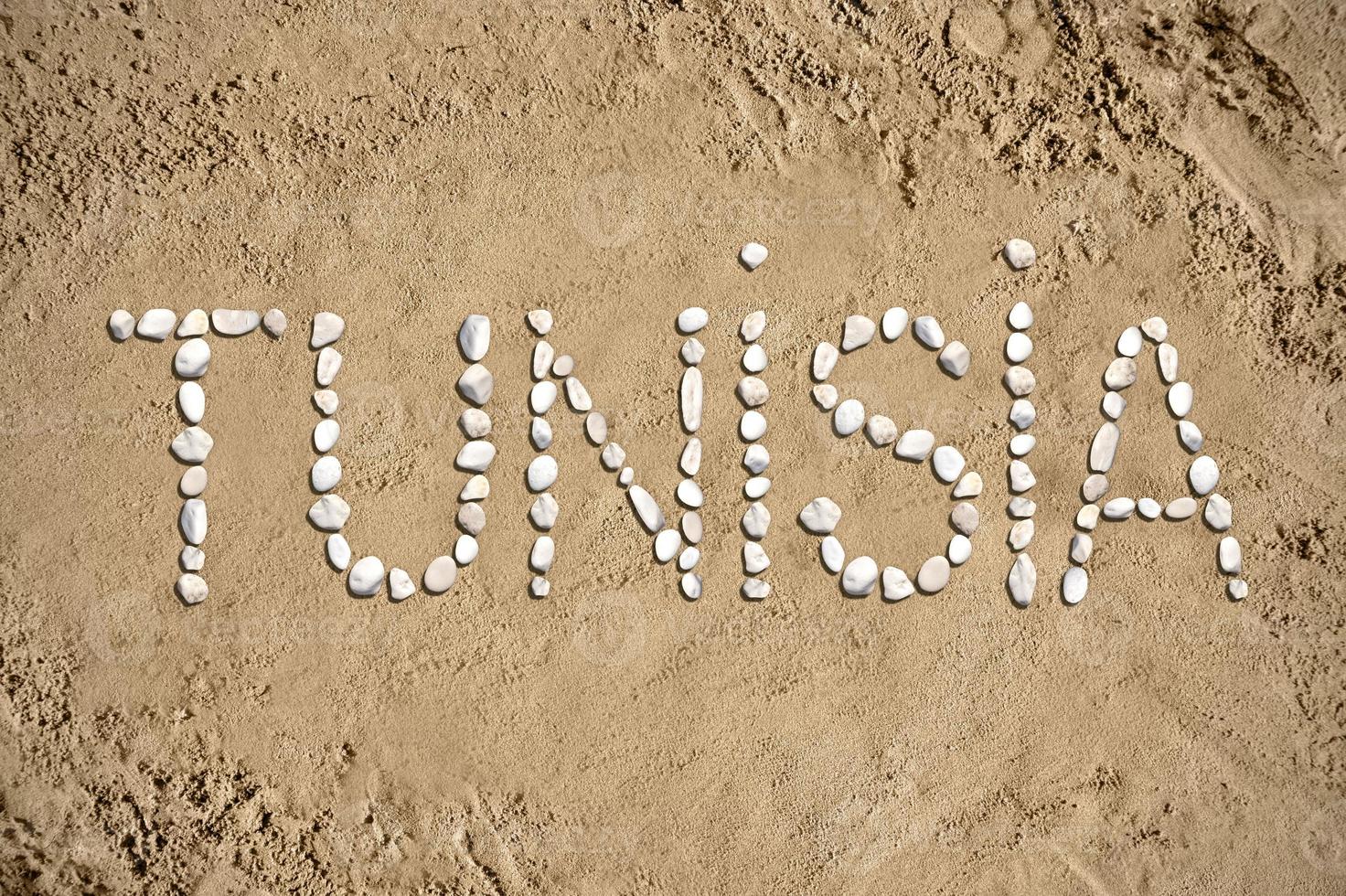 Túnez - palabra hecho con piedras en arena foto