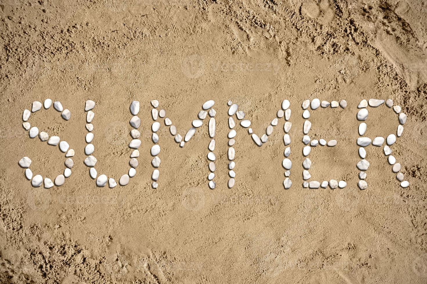 verano - palabra hecho con piedras en arena foto