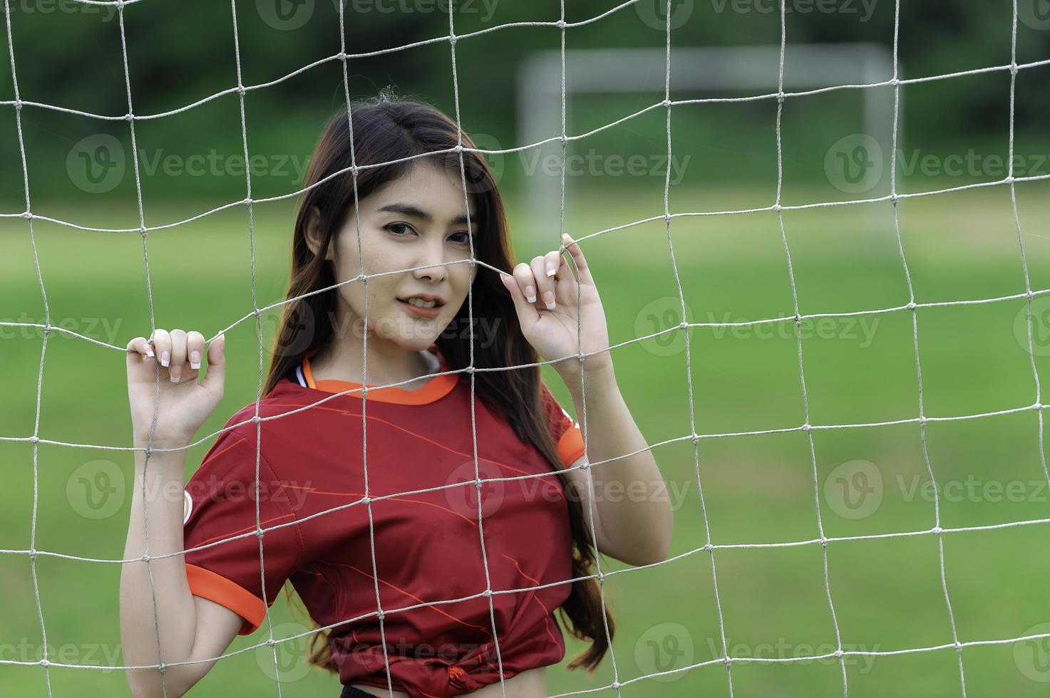 joven y hermosa mujer asiática viste a un jugador de fútbol animando el deporte, las hinchas femeninas animan el juego de fútbol foto