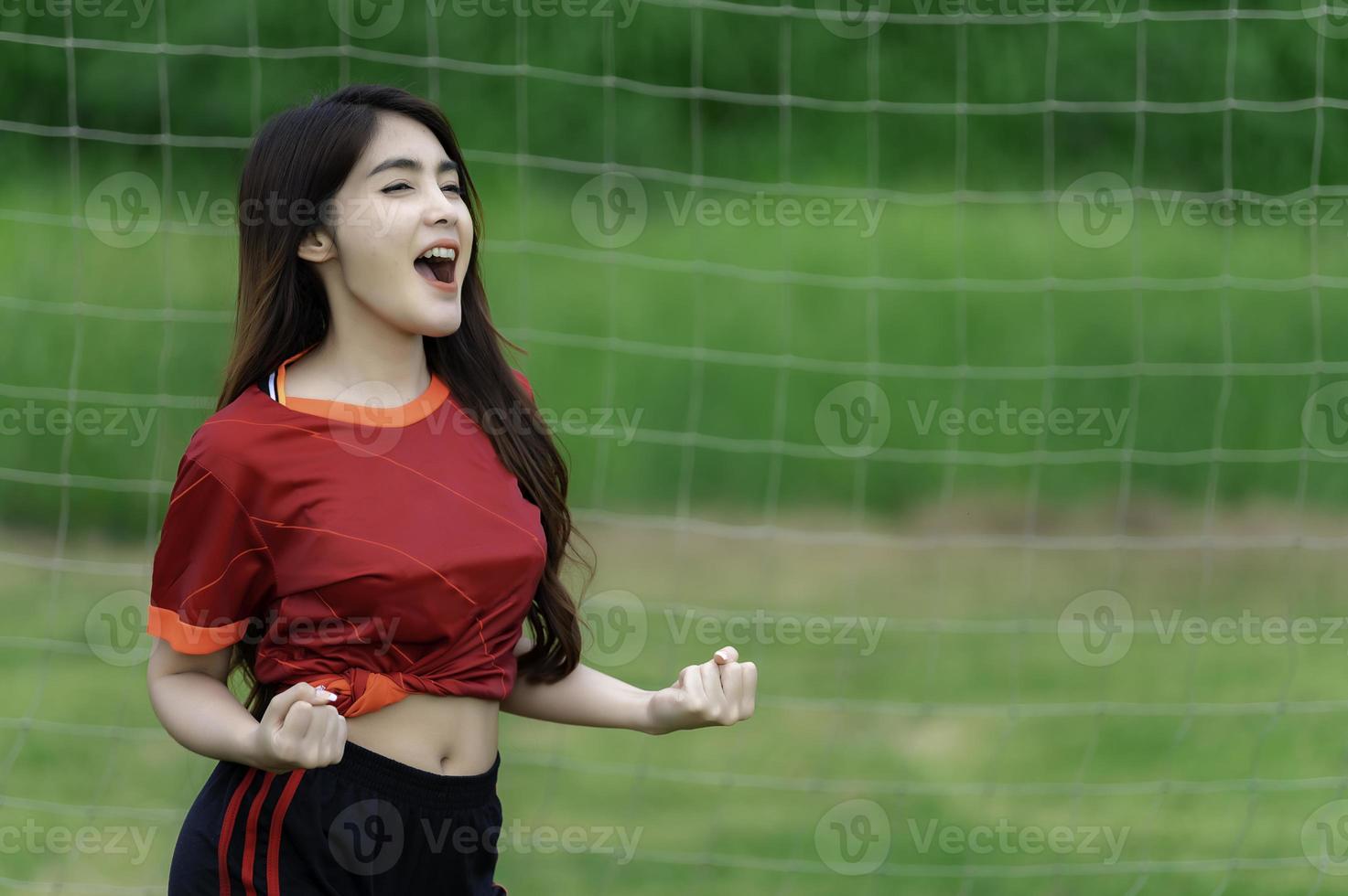 joven y hermosa mujer asiática viste a un jugador de fútbol animando el deporte, las hinchas femeninas animan el juego de fútbol foto